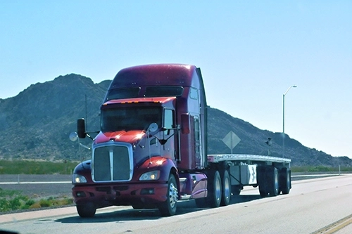 Jake brake equipped semi truck pulling a flatbed on a desert highway