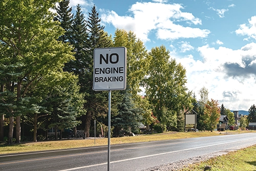 No engine braking sign posted on a residential road lined with trees